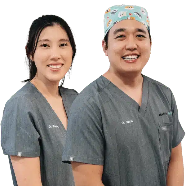Two dentists smiling in scrubs.